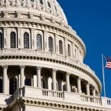 American flag waves in the wind next to the dome of the U.S. Capitol