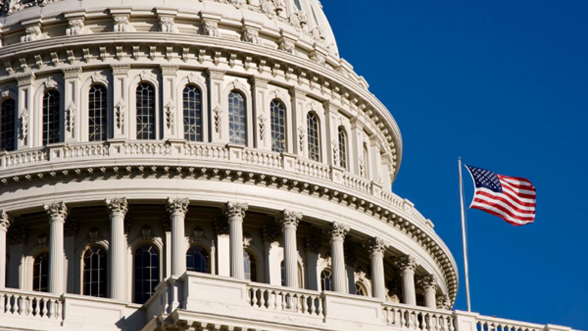 American flag waves in the wind next to the dome of the U.S. Capitol